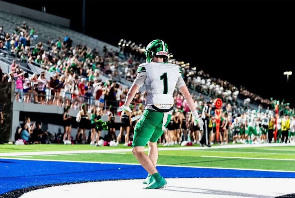 Football player wearing number 1 in a green and white uniform at night